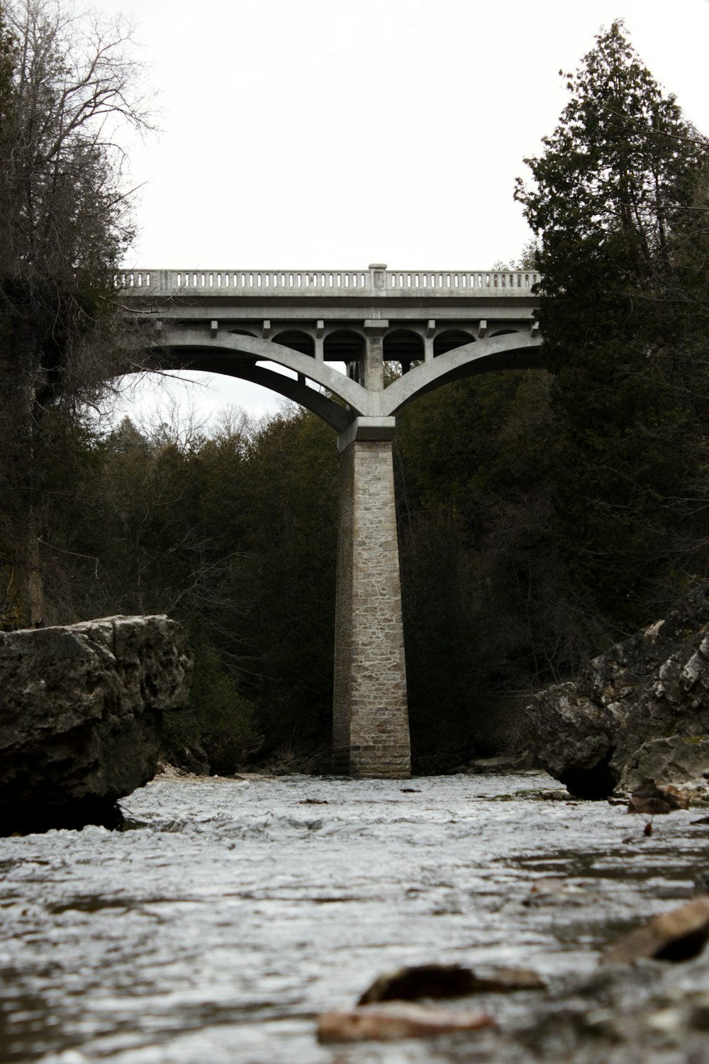 Eine Brücke über einen Fluss mit Felsen und Bäumen