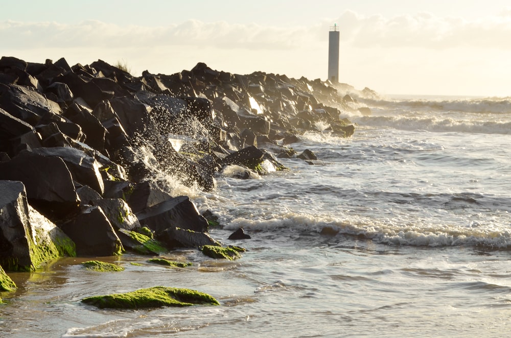 a rocky shoreline with a light house in the distance