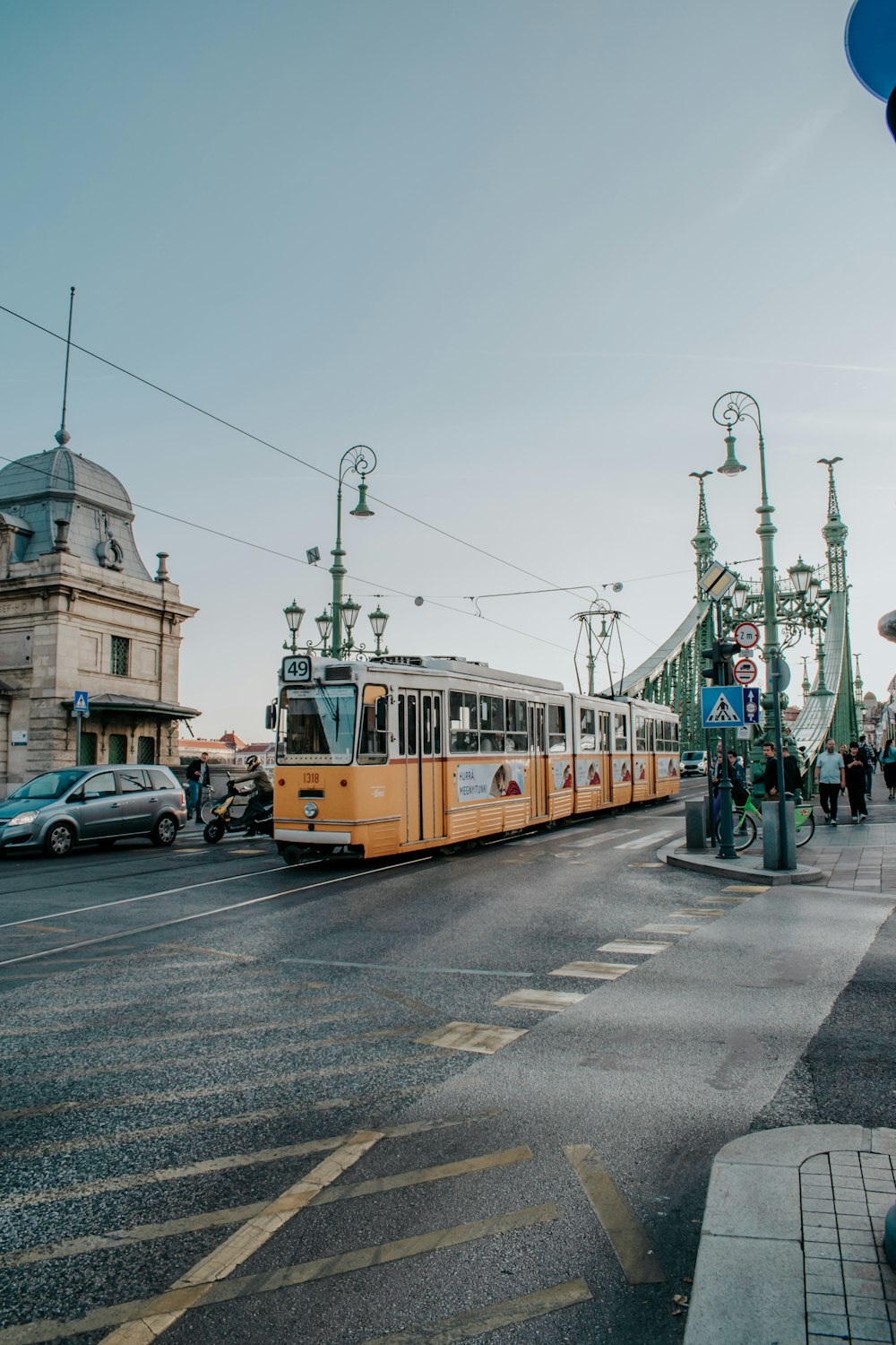 a yellow trolley car traveling down a street next to tall buildings