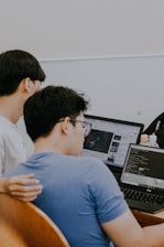 two men sitting in front of a laptop computer