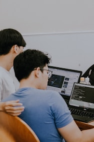 two men sitting in front of a laptop computer