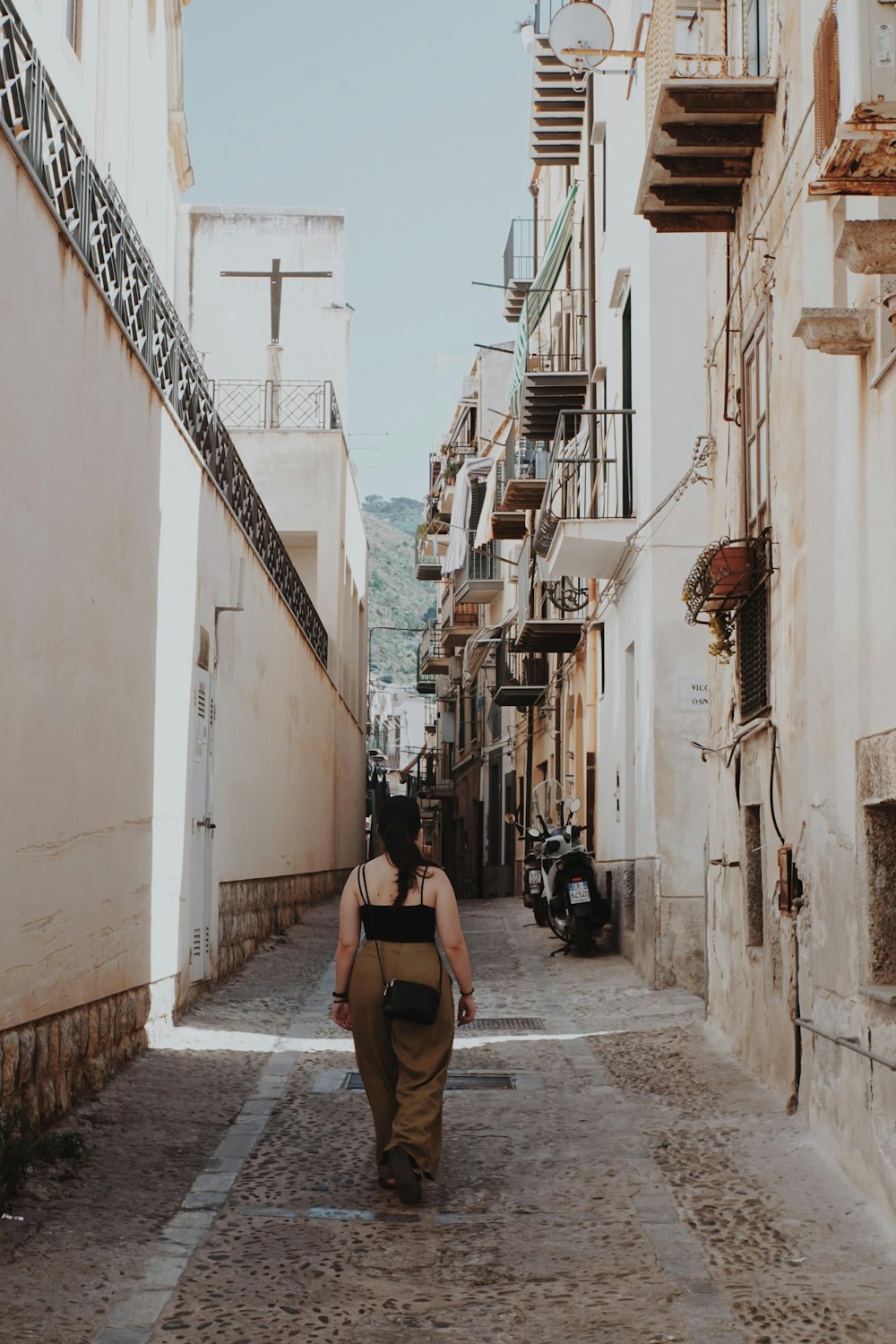 a woman is walking down a narrow street