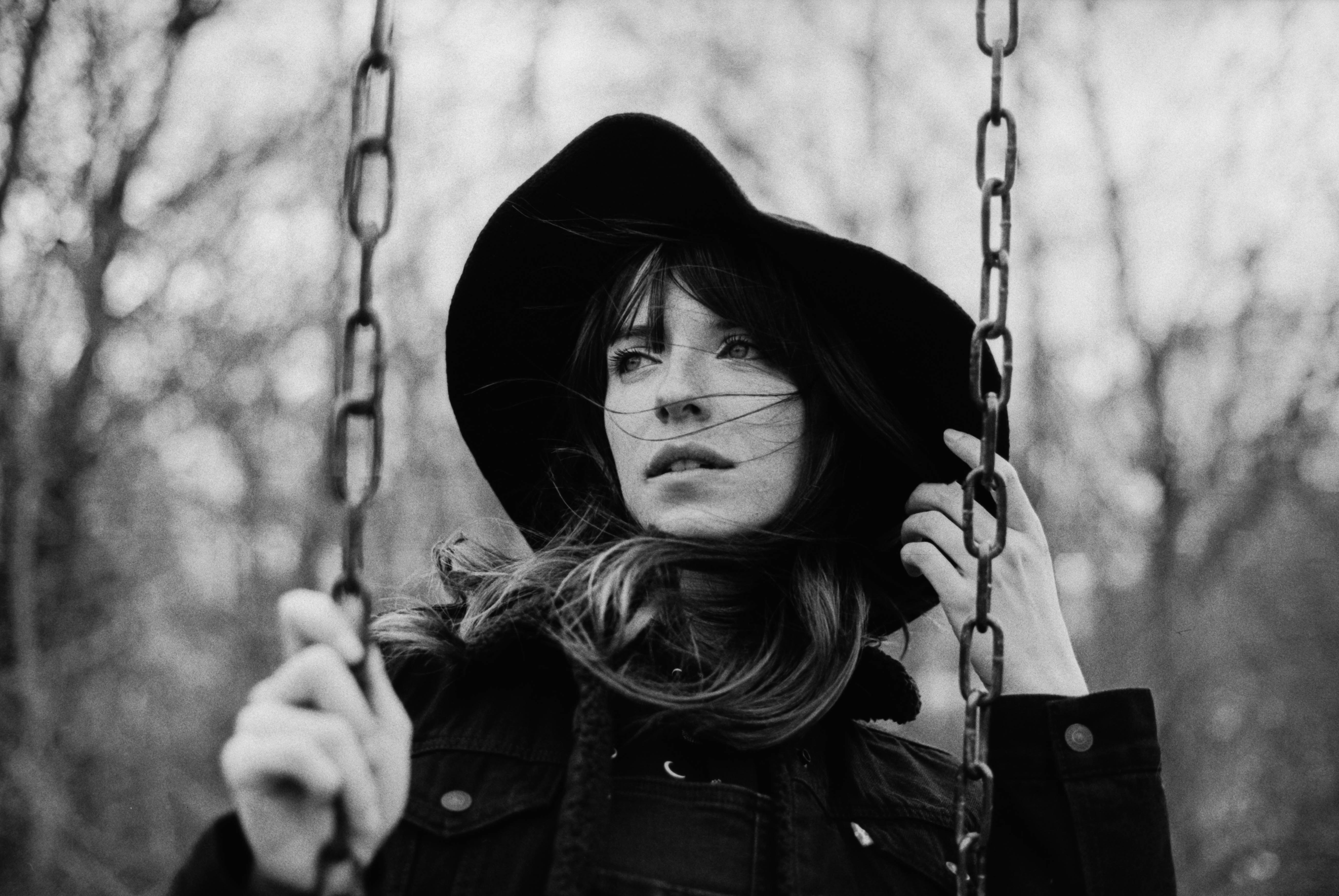 Eine Frau mit schwarzem Hut ist auf einer Schaukel