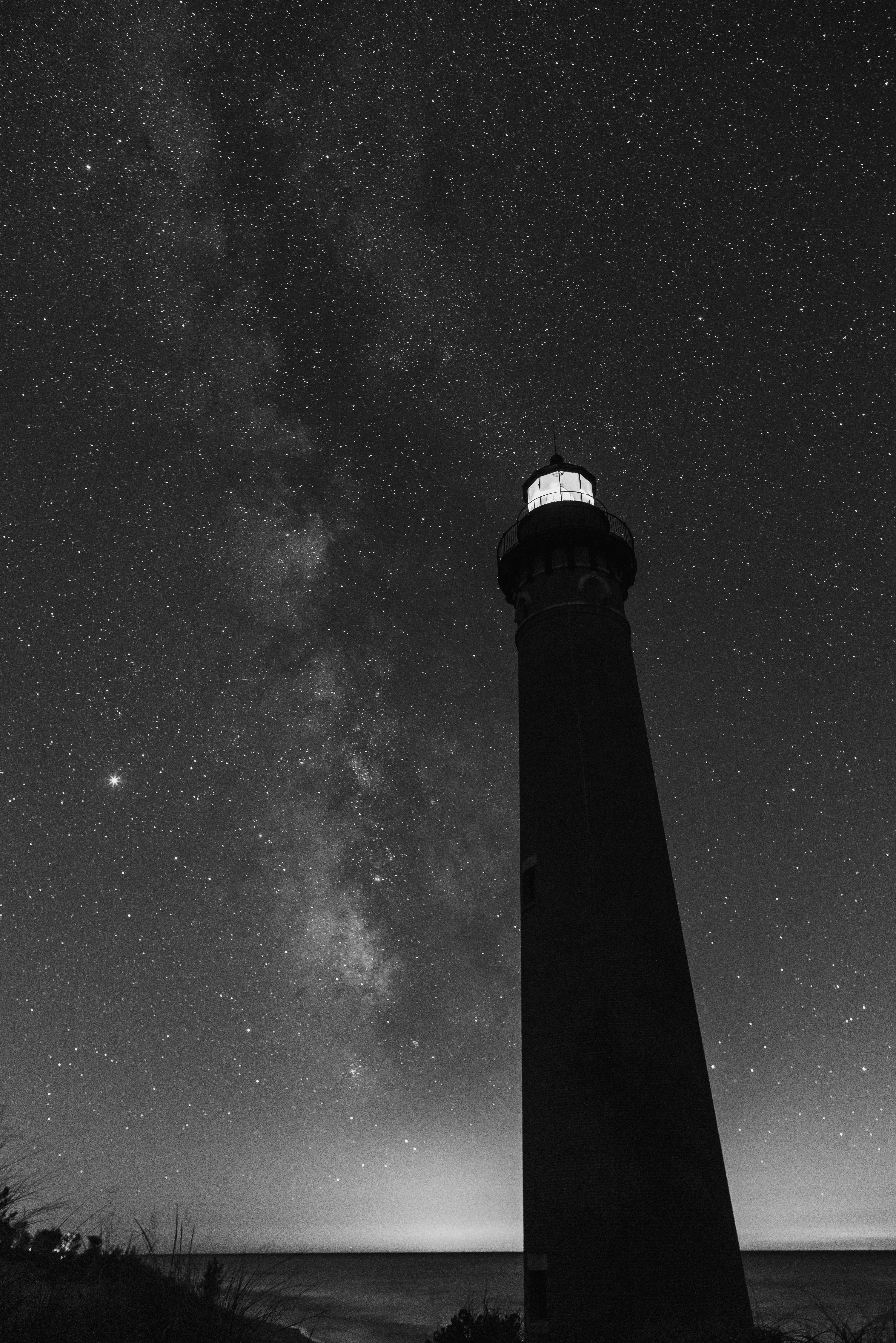 Ein Schwarz-Weiß-Foto eines Leuchtturms unter den Sternen