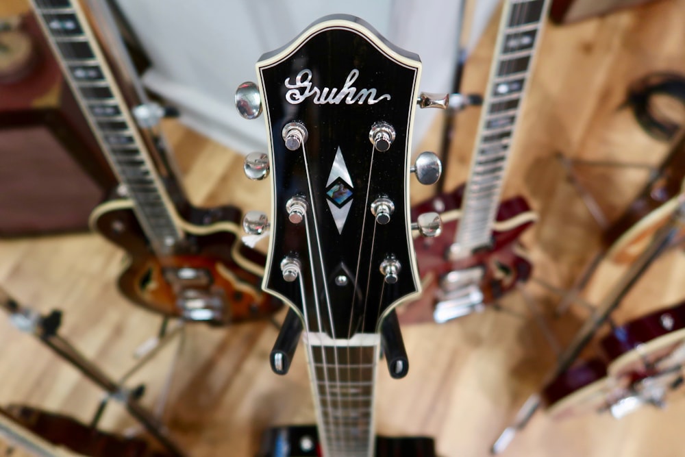 a close up of a guitar head with other guitars in the background