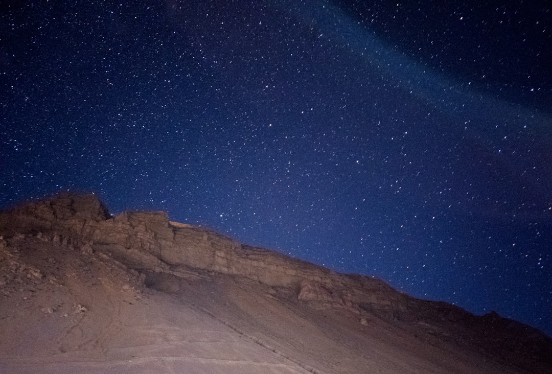 a person standing on top of a snow covered slope under a night sky,