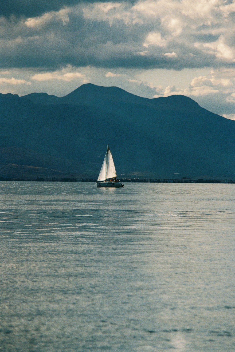 a sailboat in the water with mountains in the background