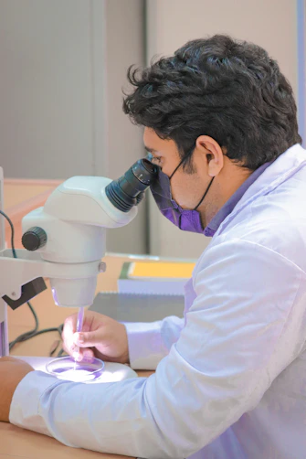 a man in a lab coat looking through a microscope