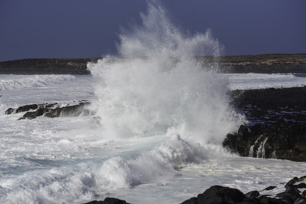 a large wave crashing into a rocky shore