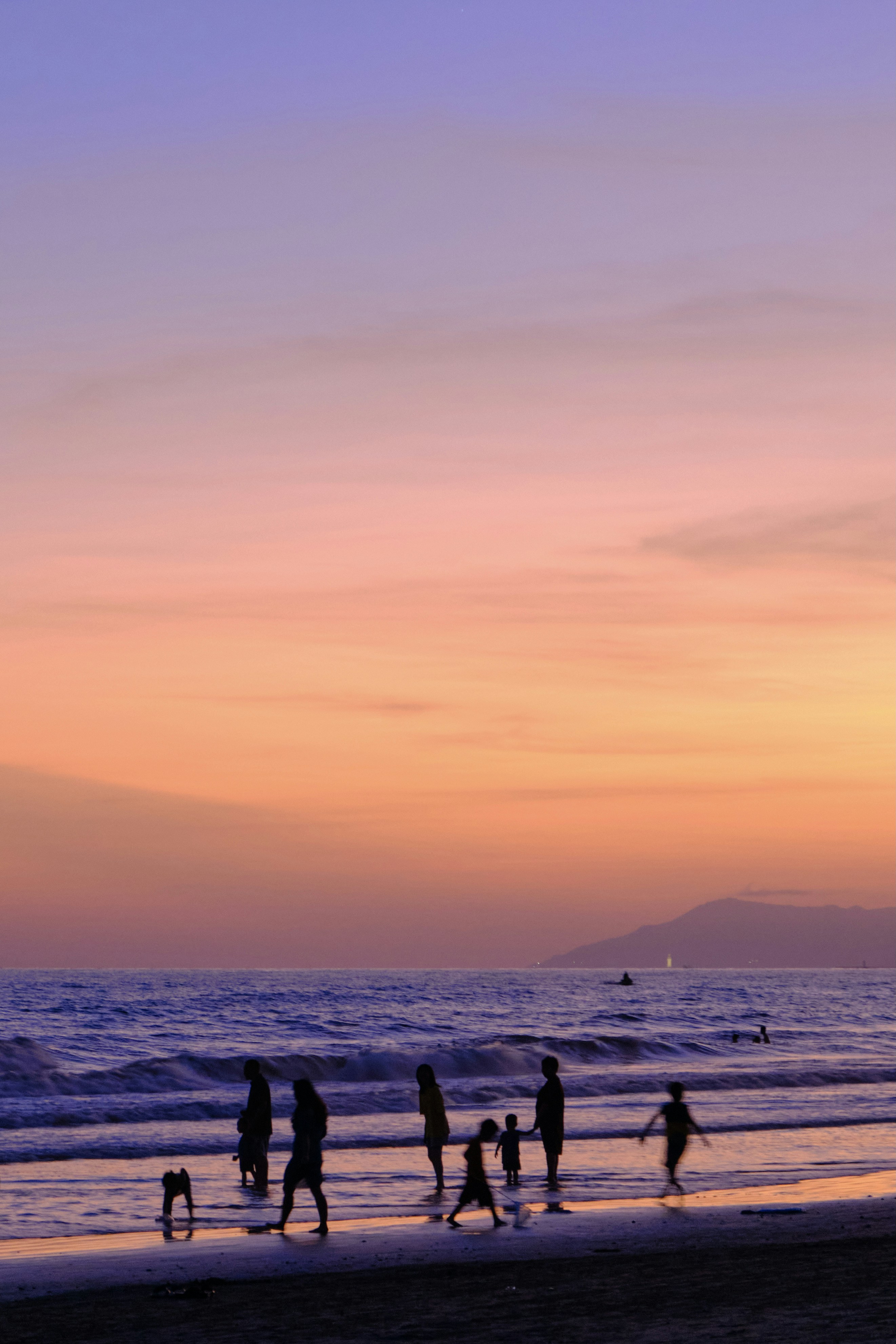 a group of people walking along a beach next to the ocean