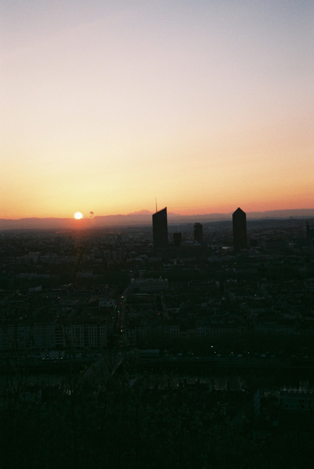 the sun is setting over a city with tall buildings