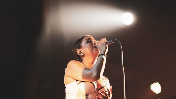 A solo performer singing into a microphone with a spotlight on them.