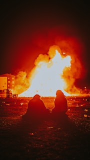 A couple sitting apart but looking towards each other, surrounded by mystical flames.