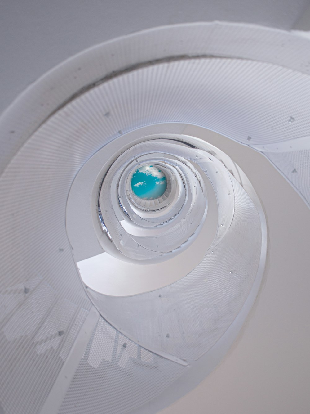 a white spiral staircase with a blue ball in the center