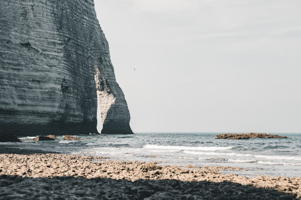 a rocky beach with a large rock formation in the background