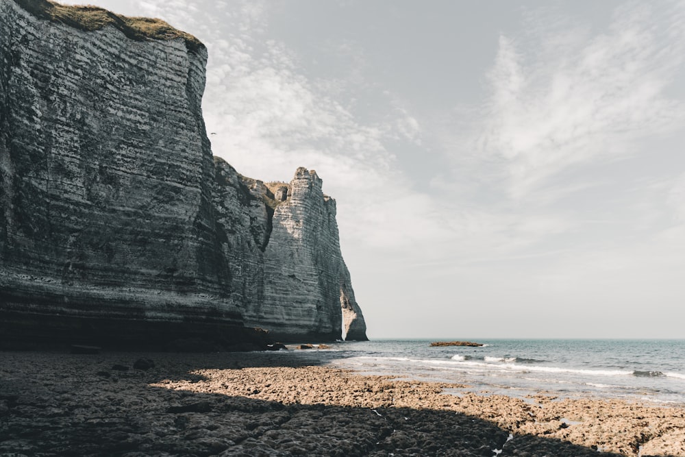 a rocky beach next to the ocean under a cloudy sky