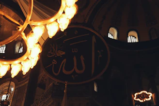 A serene study space with Islamic calligraphy art and a glowing lamp casting soft shadows.