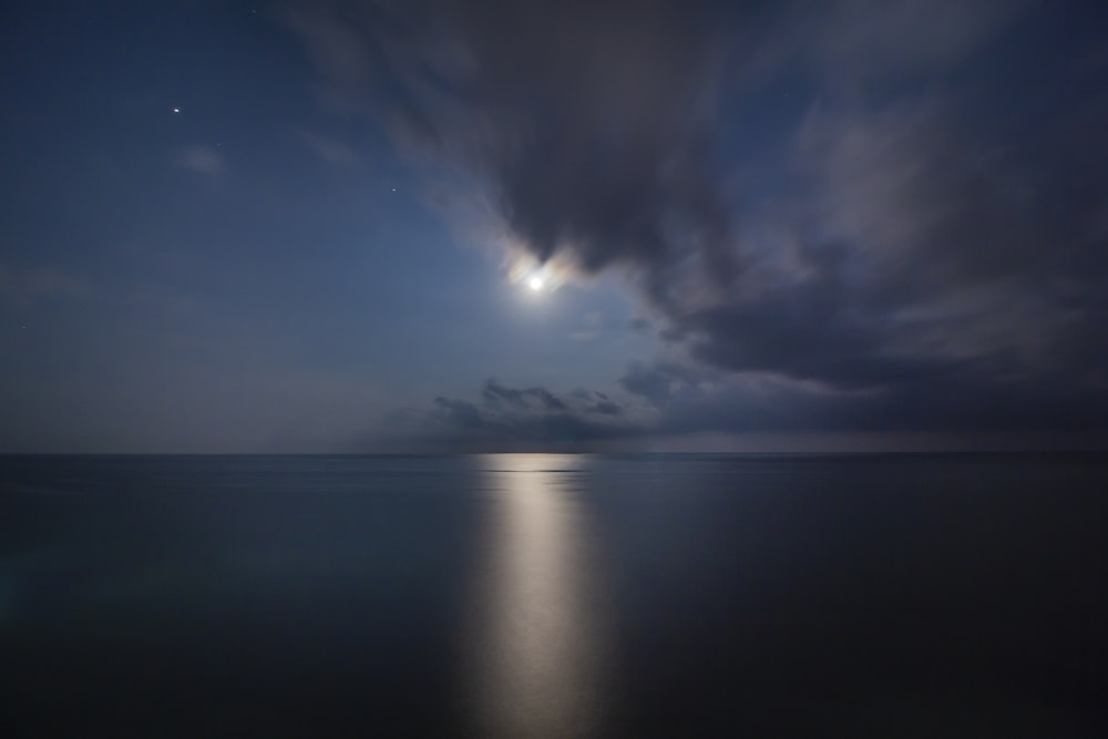 a full moon shines in the sky over the ocean