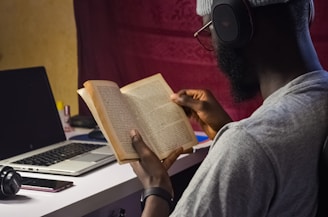 a man sitting at a desk reading a book
