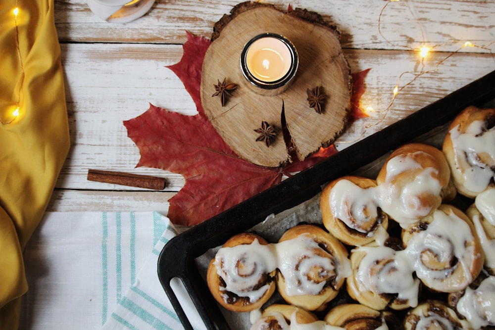 a tray of cinnamon rolls next to a candle
