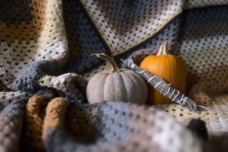 a crocheted blanket with a pumpkin and a smudge stick