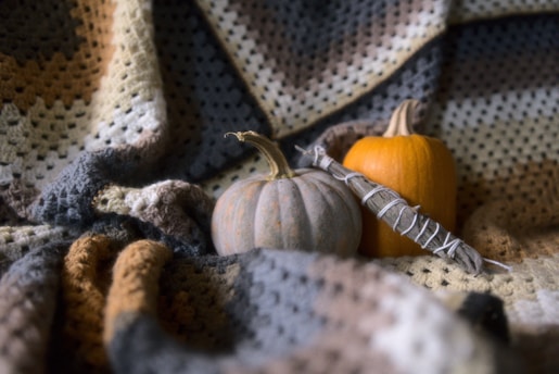 a crocheted blanket with a pumpkin and a smudge stick