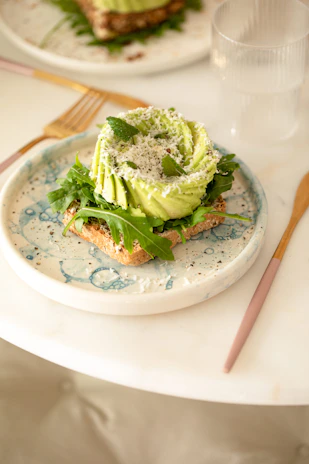 Overhead shot of a creamy avocado toast topped with radish slices and microgreens on rustic bread.