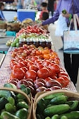 A vendor selecting ripe tomatoes from a vibrant produce display.