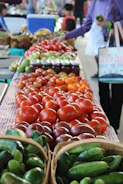 Local farmer selecting fresh vegetables in a sunlit market setting.