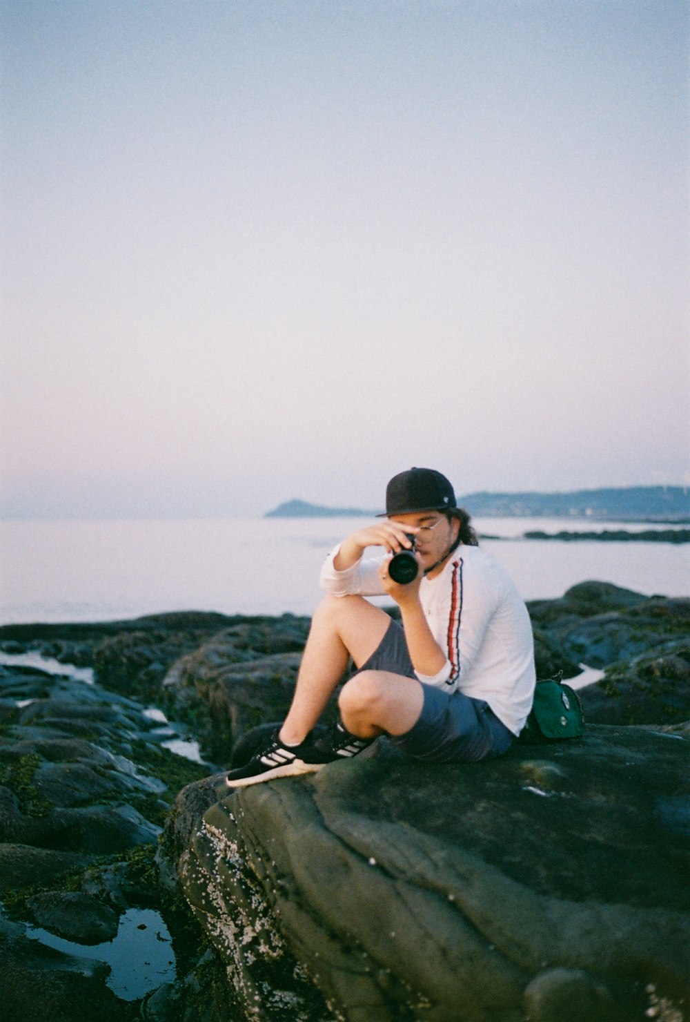 Un homme assis au sommet d’un rocher au bord de l’océan