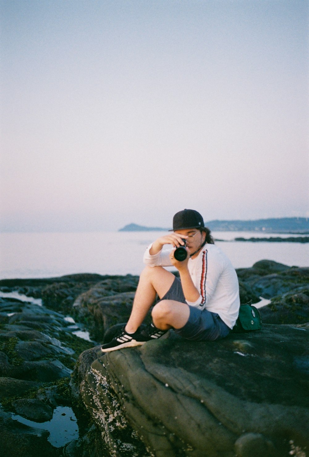 a man sitting on top of a rock next to the ocean