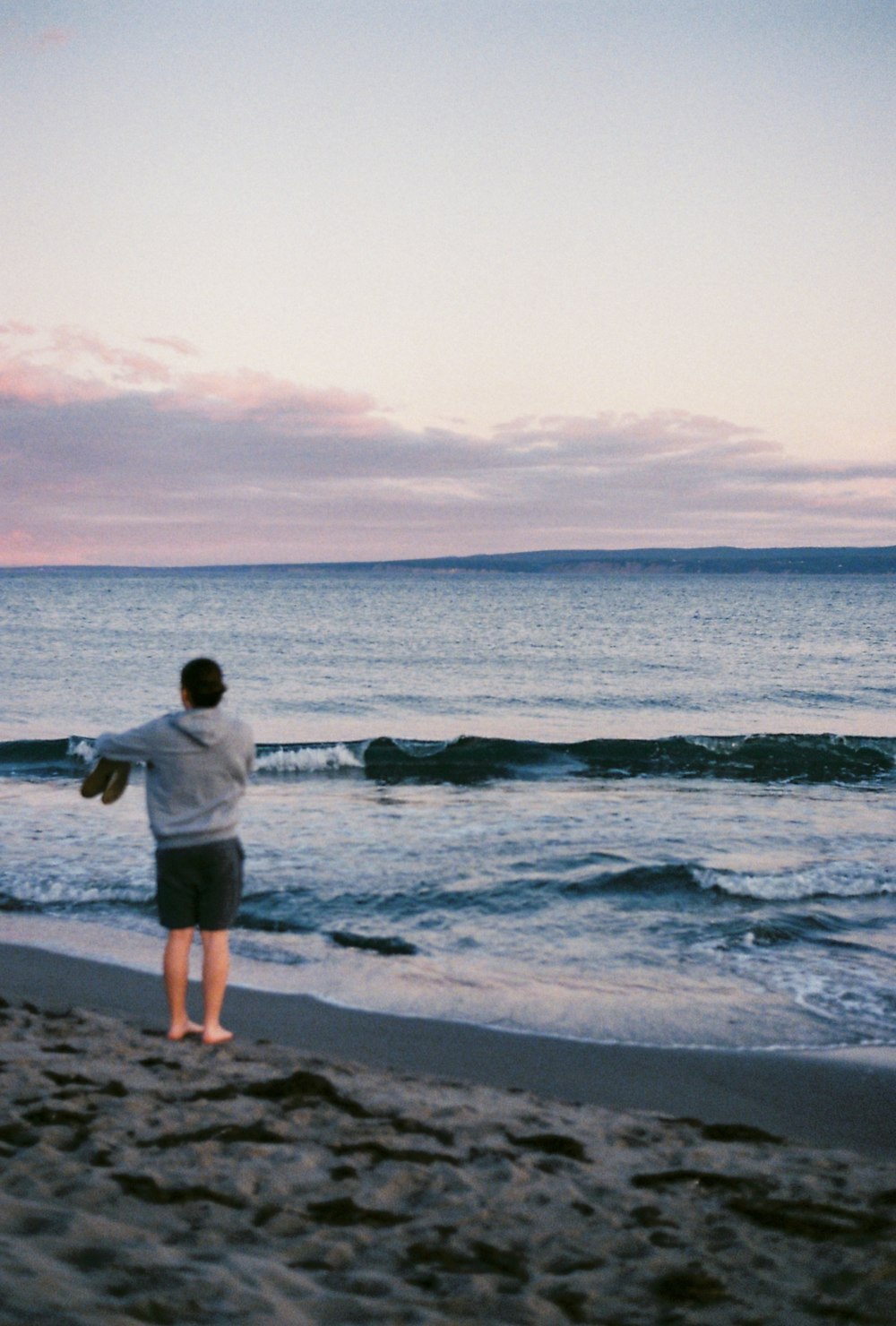 a person standing on a beach flying a kite