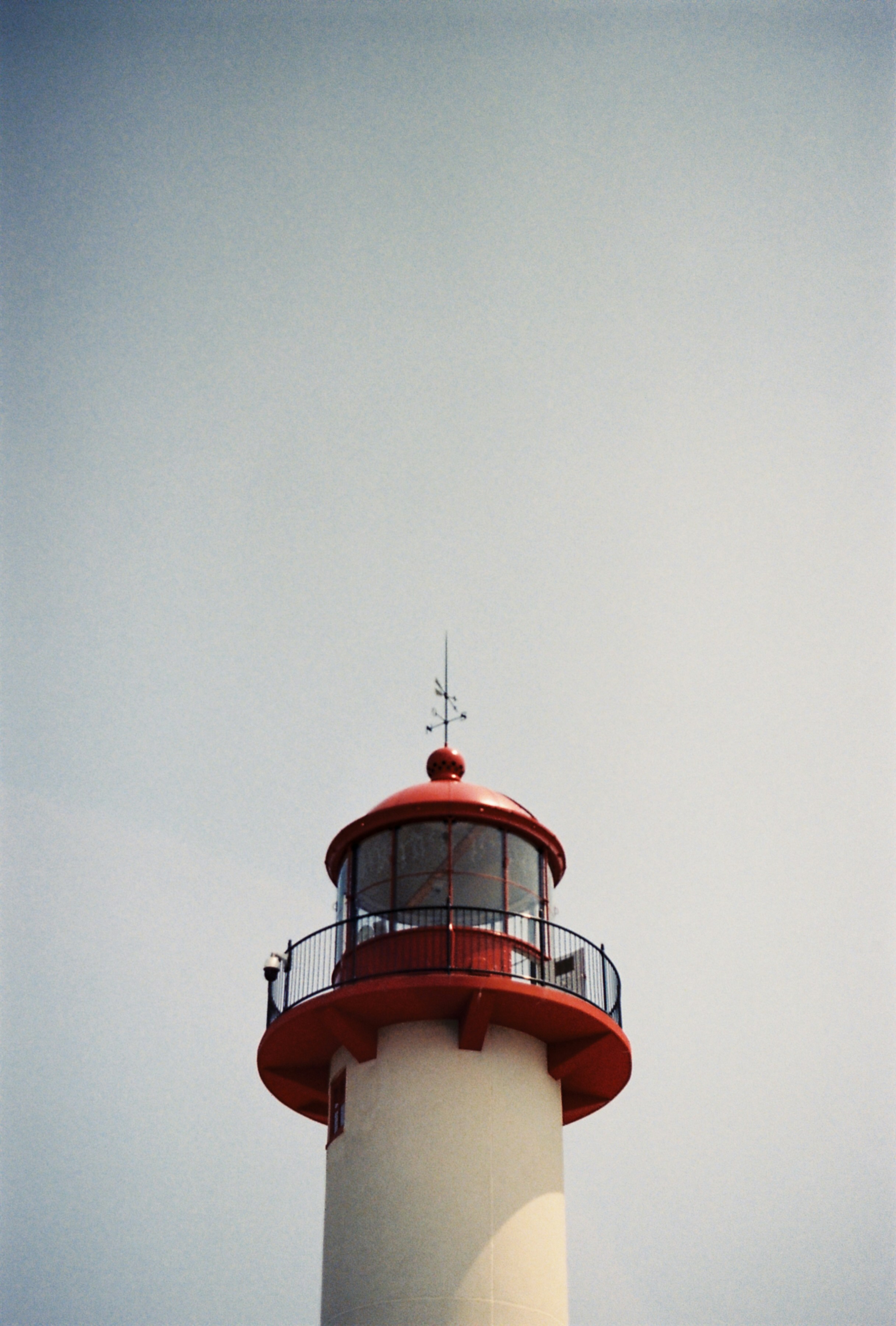 a red and white lighthouse on a cloudy day