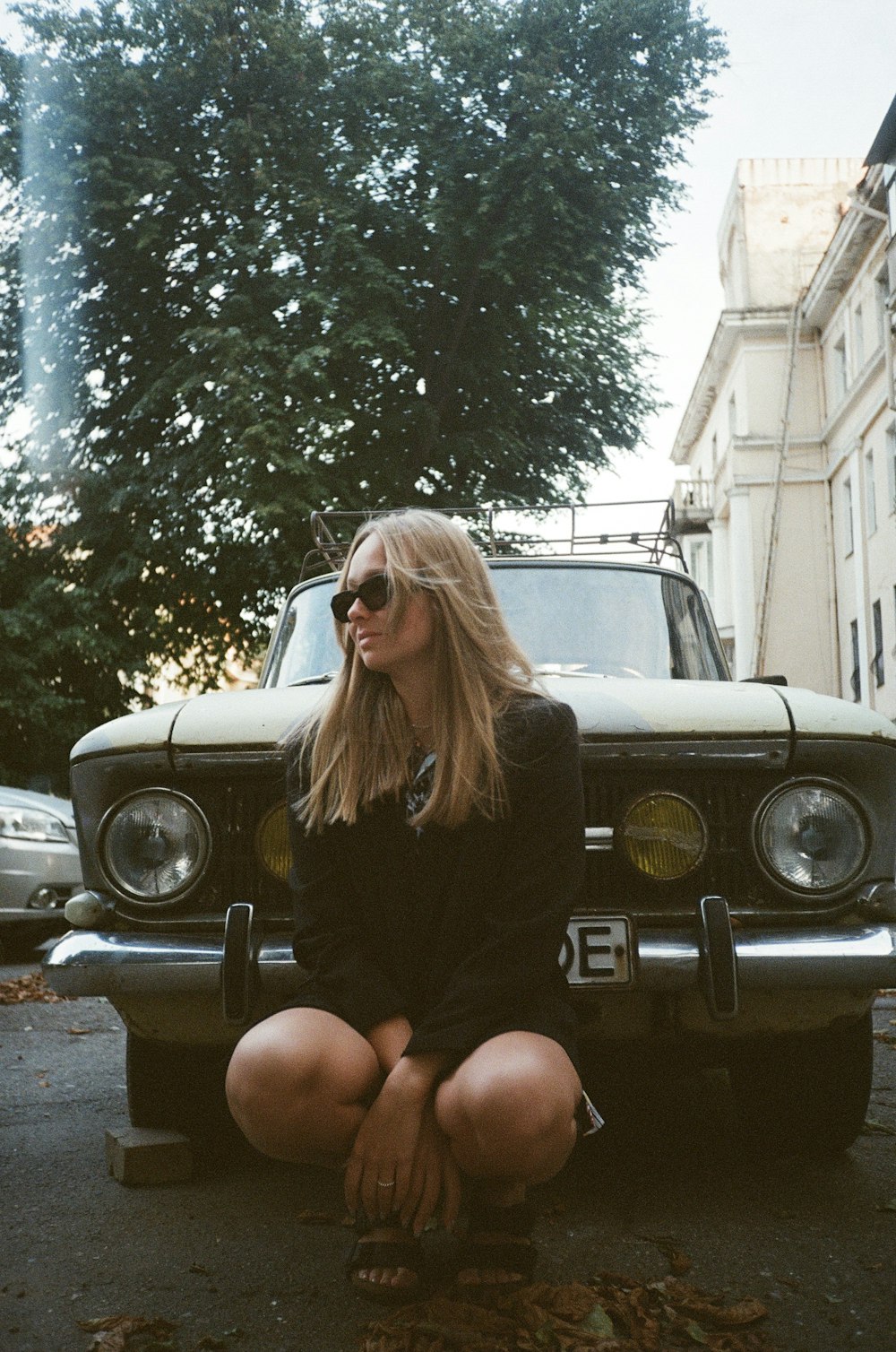 a woman sitting on the ground next to a car