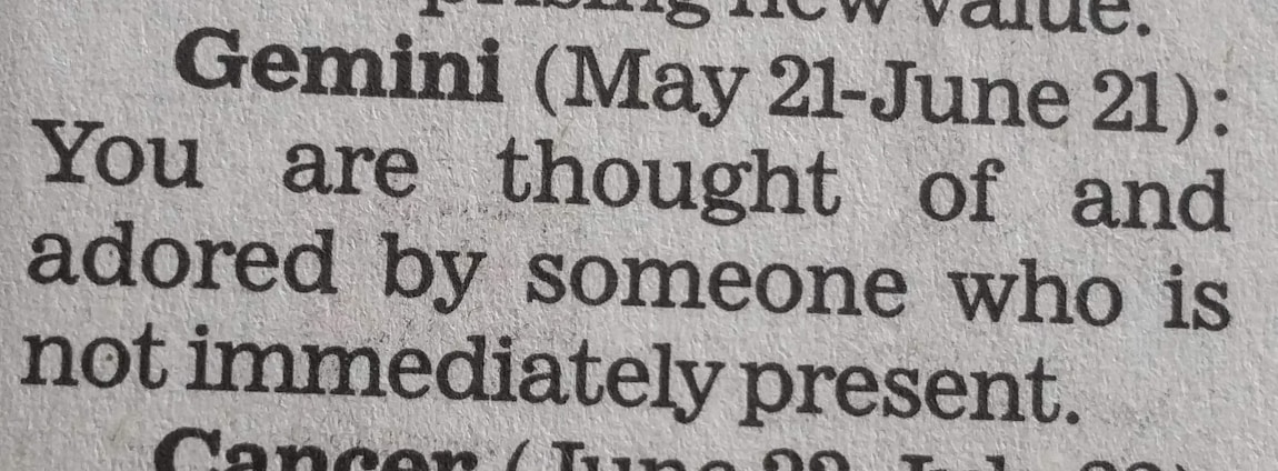 A close-up of a newspaper horoscope section, specifically the entry for Gemini from May 21 to June 21. It predicts that someone who is not present thinks of and adores the reader.