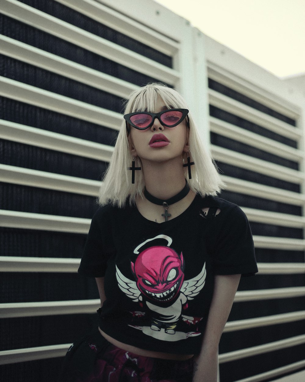 a woman with white hair wearing a black shirt and pink glasses