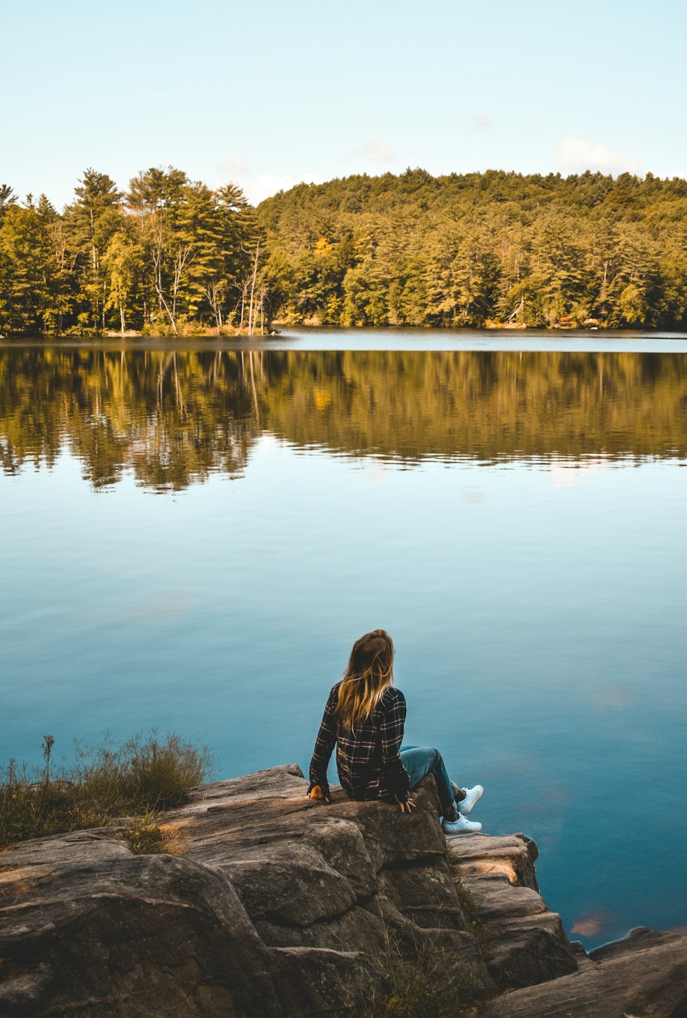 a person sitting on a rock near a lake