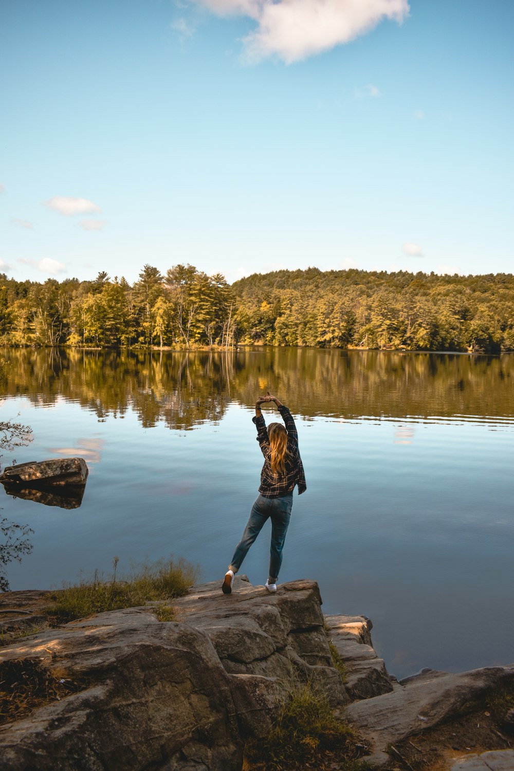 a woman standing on a rock near a body of water
