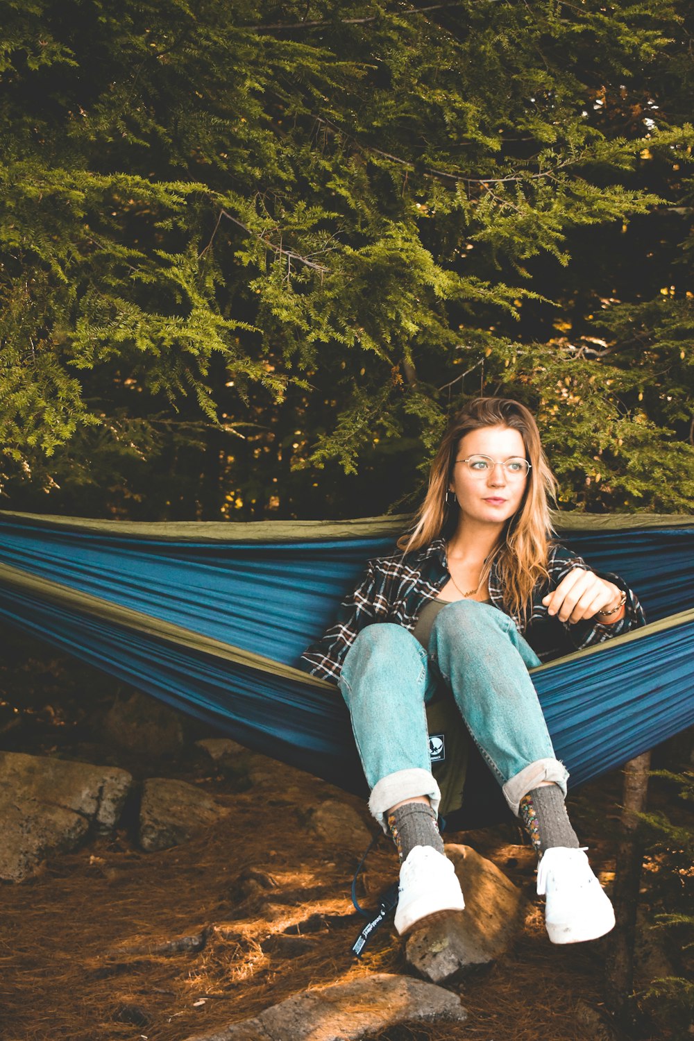 a woman sitting in a hammock in the woods