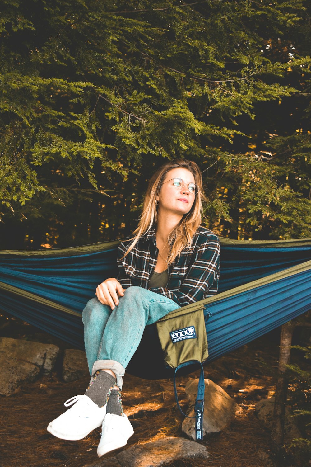 a woman sitting in a hammock in the woods