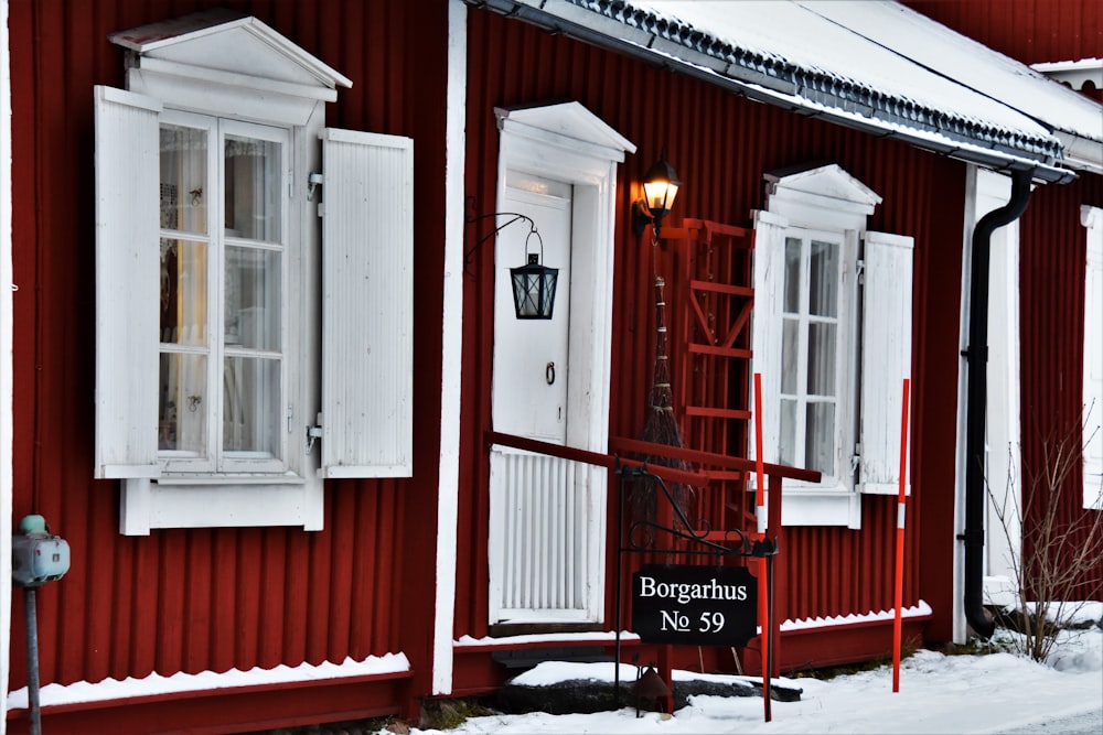 a red house with white shutters and a street sign