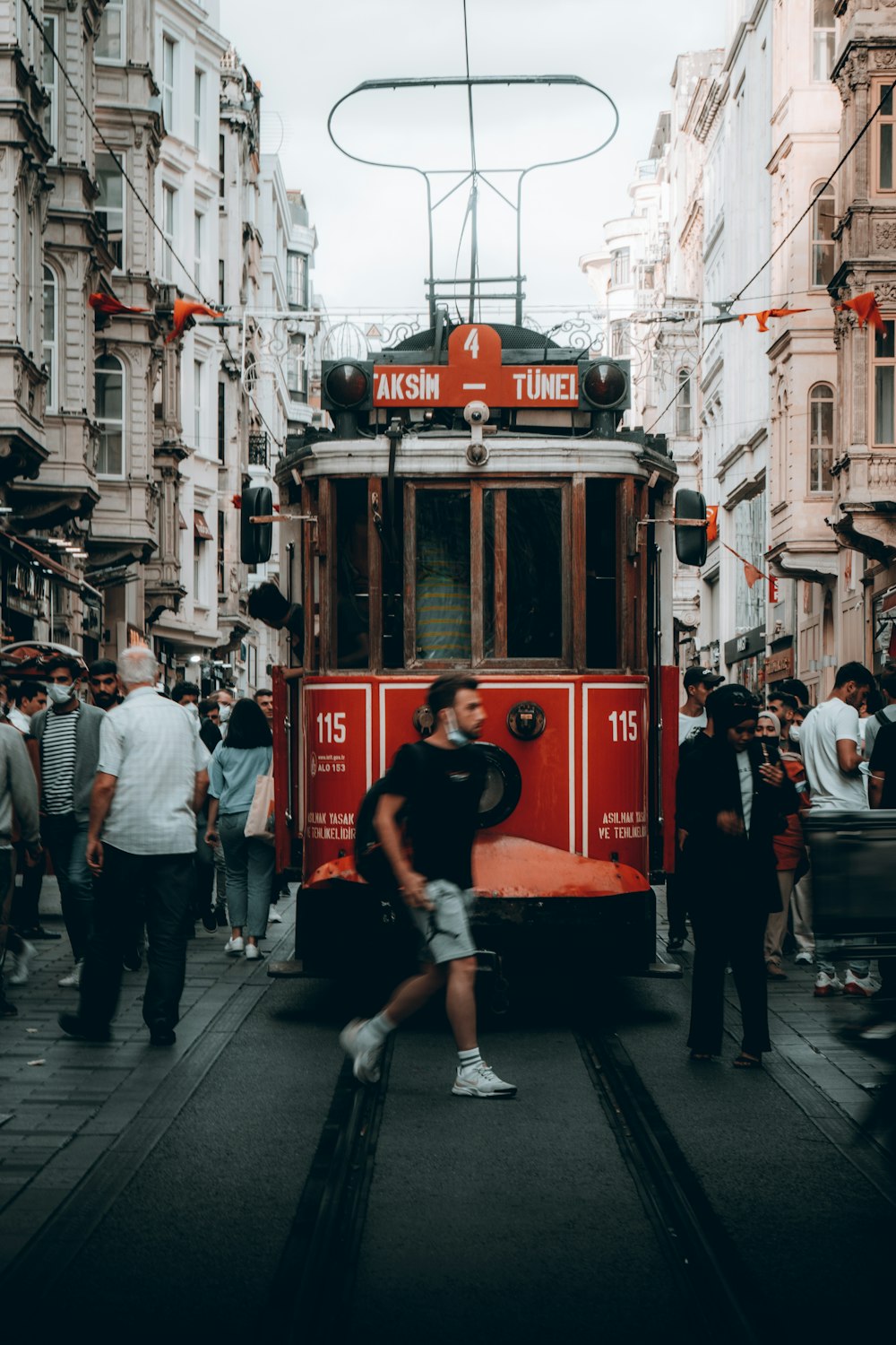 a red trolley car traveling down a street next to tall buildings