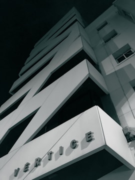 A modern, geometric building with striking, angular designs and a monochromatic exterior. The name 'Vertice' is prominently displayed on the façade.