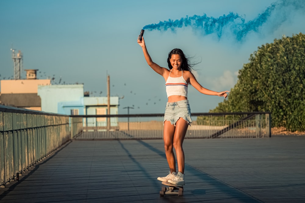 a girl is riding a skateboard with a blue smoke trail behind her