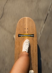 A longboard cruising smoothly down a tree-lined street, rider enjoying the breeze.