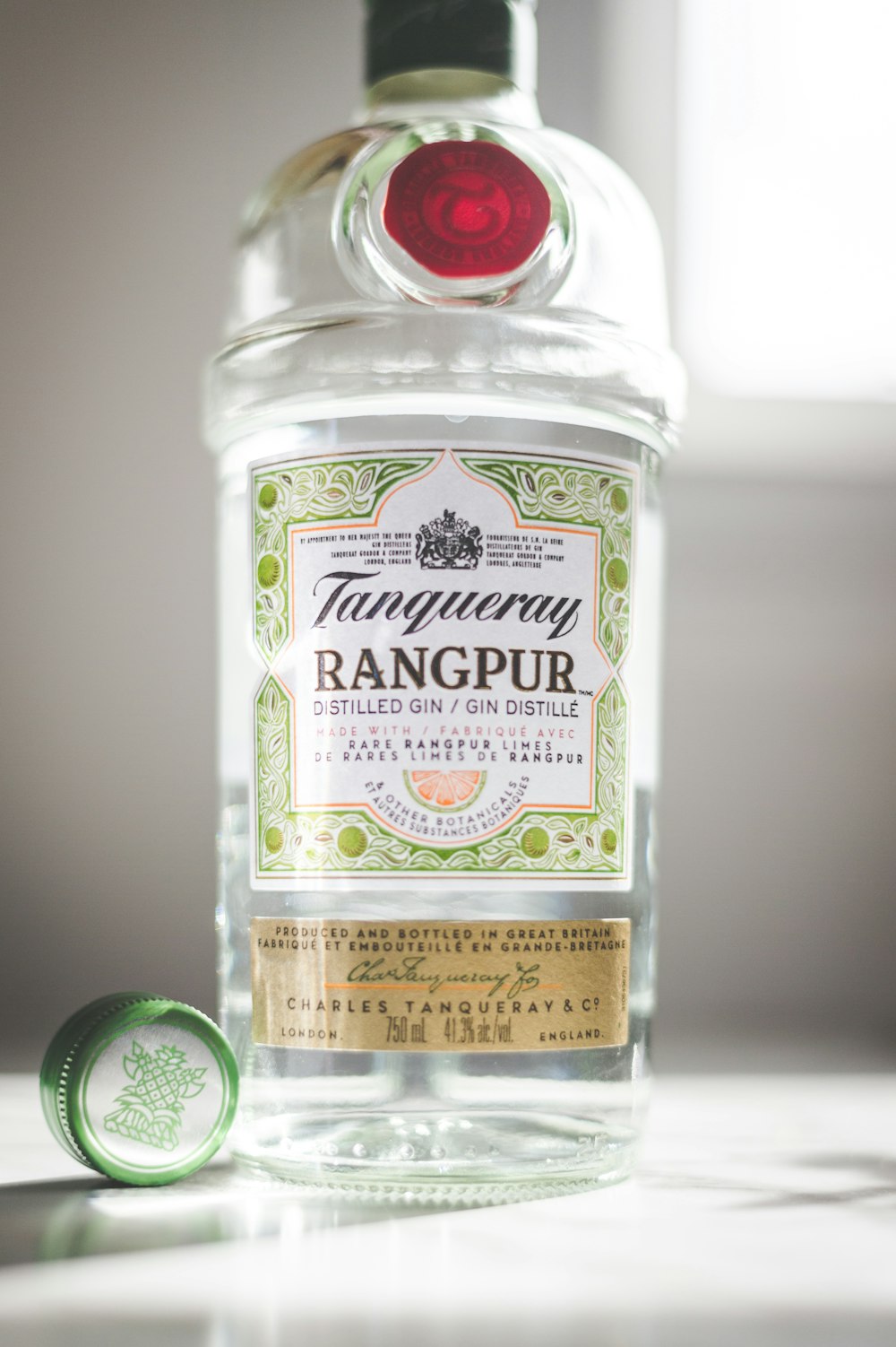 a bottle of gin with a green cap on a table