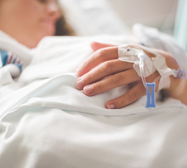 a woman laying in a hospital bed with an iv in her hand