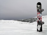 A close-up of a sleek snowboard with vibrant graphics resting on fresh snow.