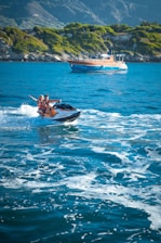 Friends laughing together on a jet ski ride across sparkling blue waters.