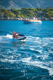 Friends laughing together on a jet ski ride across sparkling blue waters.